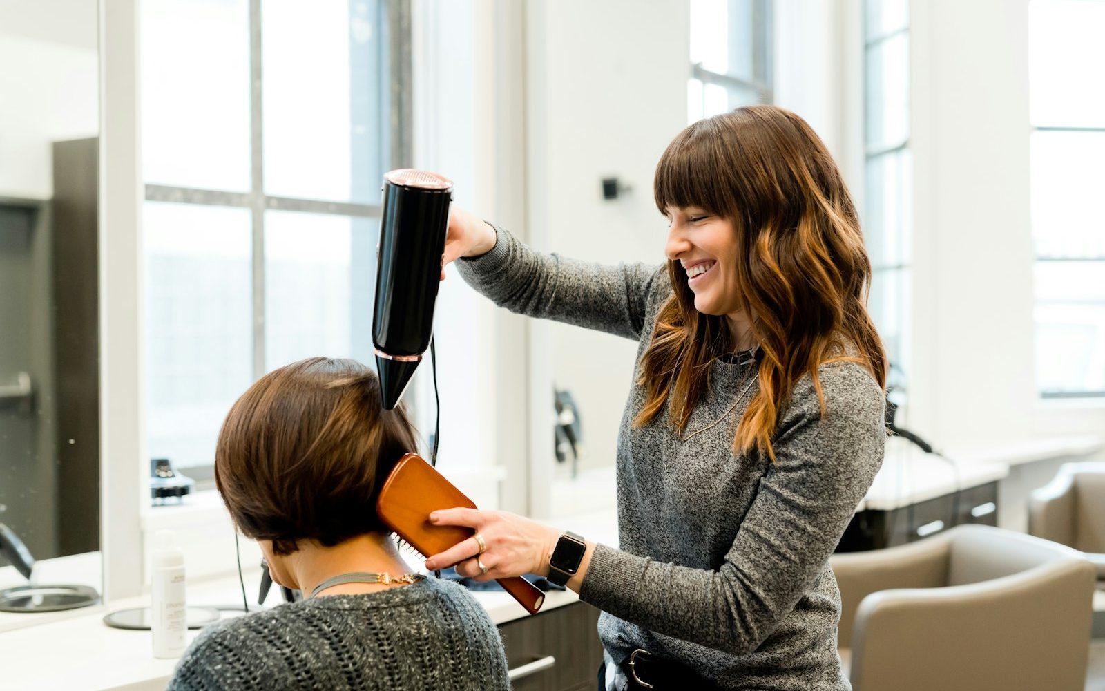 Kapster föhnt het haar van een klant in de salon